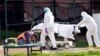 Medical personnel transport a body from a refrigerated container at Kingsbrook Jewish Medical Center, April 8, 2020, in the Brooklyn borough of New York. 