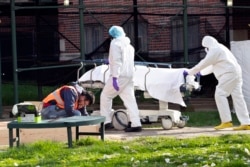 Medical personnel transport a body from a refrigerated container at Kingsbrook Jewish Medical Center, April 8, 2020, in the Brooklyn borough of New York.