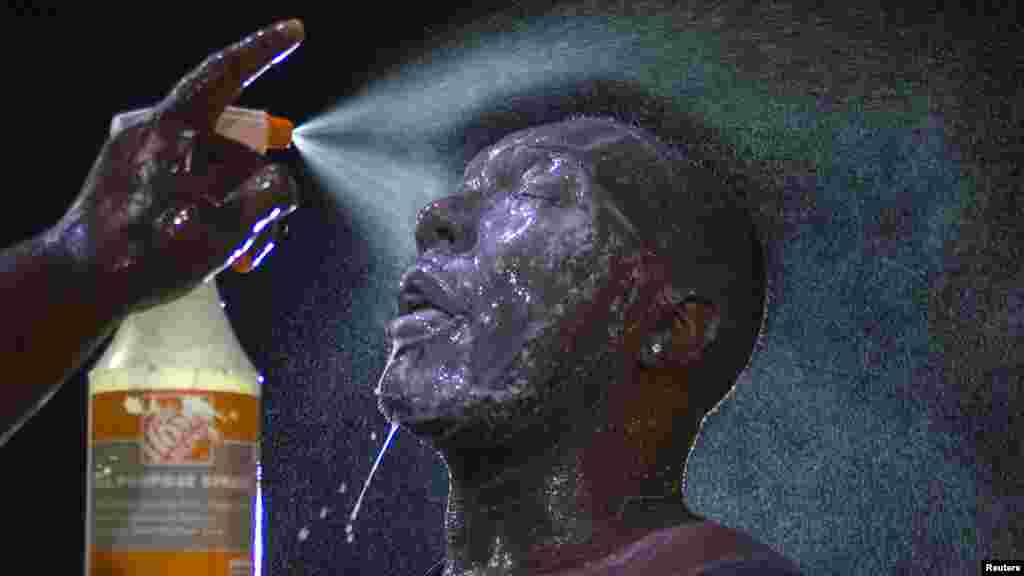 A man is doused with milk and sprayed with mist after being hit by an eye irritant from security forces trying to disperse demonstrators protesting against the shooting of unarmed black teen Michael Brown in Ferguson, Missouri, Aug. 20, 2014.