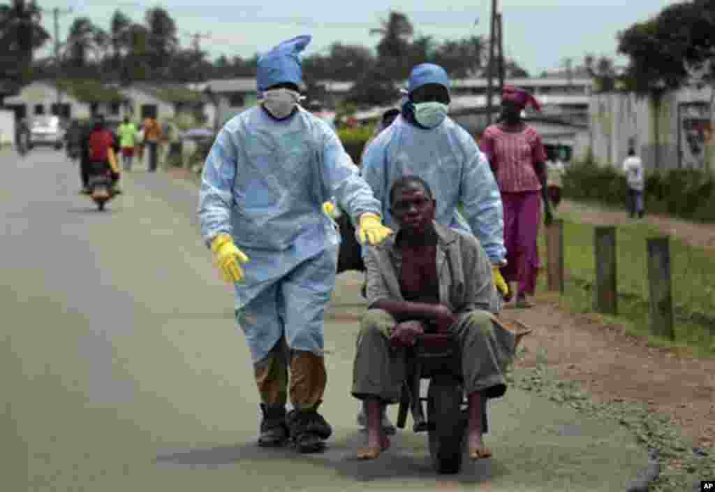 Les habitants du quartier Saint-Paul Pont couverts d’un équipement de protection individuelle transportent un homme soupçonné de porter le virus Ebola à la Clinique île à Monrovia, au Libéria, le dimanche 28 septembre 2014.Six months into the world’s worst-ever Ebola outbreak, a