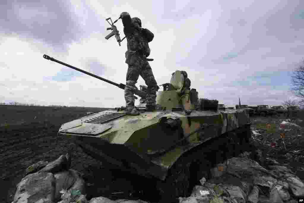 A Ukrainian soldier stands atop an armored vehicle at a military camp near the village of Michurino, Ukraine.