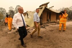 Australian Prime Minister Scott Morrison, front left, and Darren Chester, MP, tour the damaged Wildflower farm owned by Paul and Melissa Churchman in Sarsfield, Victoria, Jan. 3, 2020.