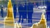 In this April 8, 2016 file photo, people are reflected on the electronic board of a securities firm in Tokyo. The IMF downgraded its outlook for growth for most regions and for the global economy as a whole. 