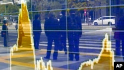 Bayangan orang di papan elektronik sebuah perusahaan sekuritas di Tokyo. 