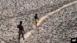 ARCHIVES - Un homme et un garçon traversent le lit asséché de la rivière Yamuna à New Delhi, en Inde, le lundi 2 mai 2022.
