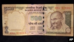 This photo illustration shows a 500 rupee Indian currency note which is being withdrawn from midnight Tuesday, in New Delhi, Nov. 8, 2016.