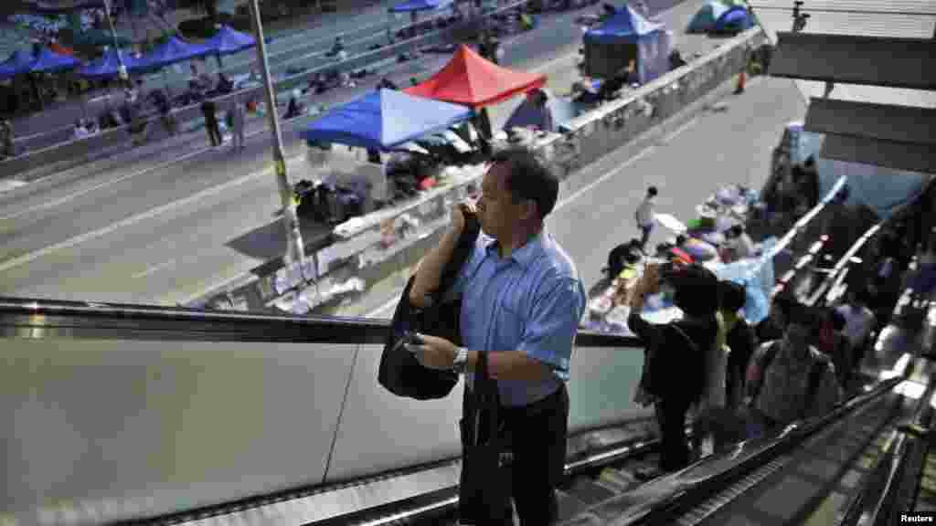 Government employees arrive to work as they walk along an area occupied by protesters outside of the government headquarters building in Hong Kong, Oct. 6, 2014.