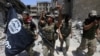 FILE - Members of the Emergency Response Division hold an Islamic State flag that they pulled down as they celebrate in the Old City of Mosul, Iraq, July 8, 2017. Islamic State fighters have mostly been pushed out of Iraq and Syria but are far from defeated, analysts say.