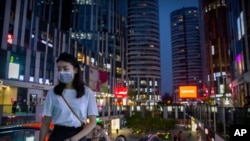 People wearing face masks to protect against the coronavirus ride an escalator at a shopping and office complex in Beijing, July 16, 2020. 