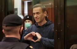 FILE - A still image taken from video footage shows Russian opposition leader Alexey Navalny making a hand gesture forming a heart during the announcement of his court verdict in Moscow, Russia, Feb. 2, 2021.
