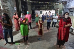 Indians, wearing face mask and maintaining physical distance, participate in religious rituals during Navratri or nine nights festival celebrations in Ahmedabad, Oct. 21, 2020.