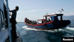 Polisi menjaga perahu kayu yang membawa pengungsi Rohingya dari Myanmar menuju Australia. 