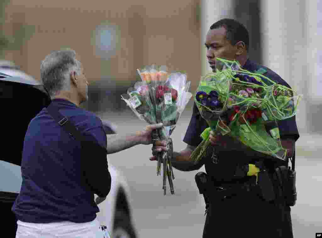 Seorang polisi di Dallas, Texas menerima bunga tanda simpati dari seorang warga, pasca insiden penembakan polisi di sana (9/7). (AP/Eric Gay)