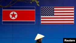 Seseorang berjalan melewati spanduk yang menunjukkan bendera Korea Utara dan AS menjelang KTT Korea Utara-AS di Hanoi, Vietnam, 25 Februari 2019. (Foto: REUTERS / Kim Kyung-Hoon)