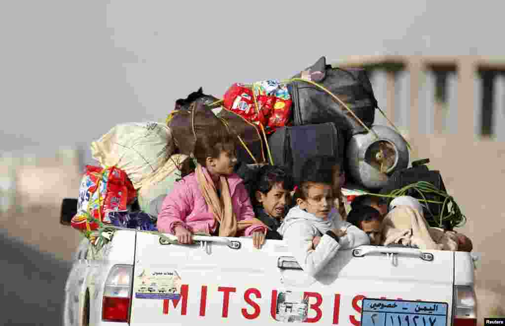 Children ride on the back of a pick-up truck with their luggage as they flee Saudi-led airstrikes in Sana'a, April 6, 2015.