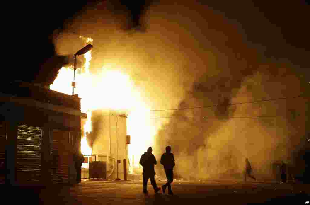 Warga menjauhi gudang yang terbakar menyusul kerusuhan setelah pengumuman dewan juri pengadilan Missouri, Senin (24/11) di Ferguson, Missouri. (AP/Jeff Roberson)