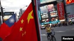 Seorang perempuan melintas di depan bendera Taiwan dan China saat demo oleh kelompok pro-China di Taipei, Taiwan, 14 Mei 2016. (Foto: Reuters)