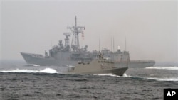 2013年1月22日，台灣海軍“光華-6”型導彈快艇（前）在高雄附近海域舉行的演習期間從一艘佩里級護衛艦旁駛過。