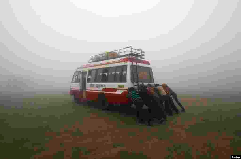Passengers push their bus amid dense fog on a cold winter morning on the outskirts of Agartala, capital of India's northeastern state of Tripura.