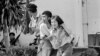 FILE - In this Oct. 6, 1976 file photo blood streaming down his face, a leftist student, center, wounded and captured by police is helped to an ambulance at the Thammasat University campus in Bangkok, Thailand.