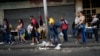 Varias personas hacen fila mientras esperan un transporte público en Caracas, Venezuela, el lunes 27 de febrero de 2023. (Foto AP/Ariana Cubillos)