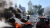 A tuk-tuk drives past burning tires during ongoing anti-government protests in Kerbala, Iraq, Dec. 23, 2019. 