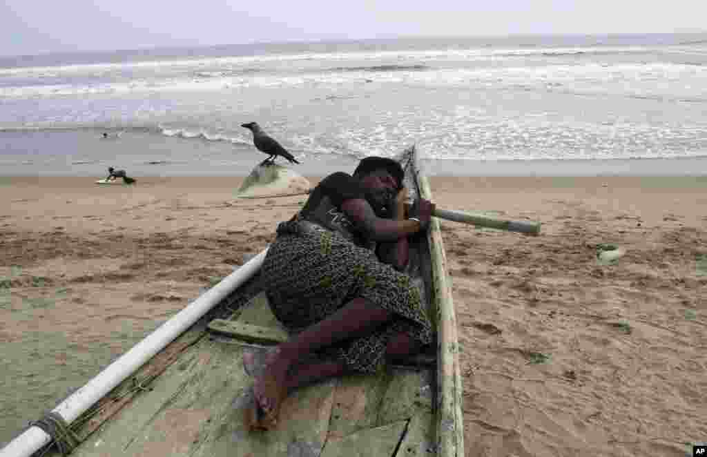 A child plays as an Indian fisherman sleeps in his anchored fishing boat on the Bay of Bengal coast at Puri, Odisha state, India, Oct. 10, 2013.