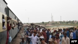 Railway workers repair the tracks next to damaged carriages a day after the derailment of a passenger train in Nawabshah on Aug. 7, 2023.