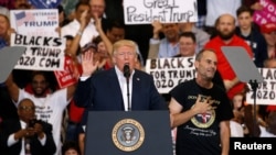 A supporter invited onstage by U.S. President Donald Trump puts his hand to his chest during a "Make America Great Again" rally at Orlando Melbourne International Airport in Melbourne, Florida, Feb. 18, 2017.