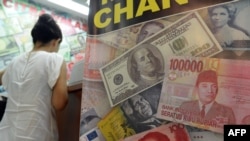 Lembaran uang dolar Amerika, rupiah dan yuan dalam poster pedagang penukaran valas yang terpajang di Jakarta, 12 Juni 2013.