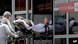Healthcare workers take on a stretcher a patient suspected of having COVID-19 from an ambulance into the HRAN public hospital in Brasilia, Brazil, March 23, 2021.