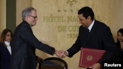 Jeffrey DeLauretis, encargado de asuntos de EE.UU. en Cuba estrecha la mano del viceministro de Transporte cubano Eduardo Rodríguez Ávila luego de firmar un acuerdo de cooperación para la limpieza, prevención y contención de derrames tóxicos en sus respectivas aguas en el Golfo de México.