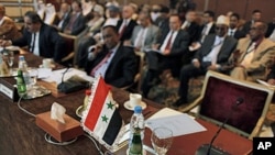 Le drapeau syrien et une affiche écrite en arabe "la république syrienne" est posée sur la chaise vide lors d'une réunion au Caire, Egypte, le 12 février 2012.