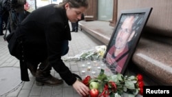 A woman places an apple next to a portrait of Apple founder and former CEO Steve Jobs, outside an Apple store in central Moscow, Oct. 6, 2011. Jobs died at the age of 56 after a long battle with pancreatic cancer.