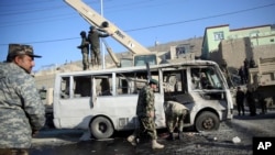 Petugas keamanan Afghanistan menginspeksi minibus yang hancur akibat serangan bom bunuh diri di Kabul, Afghanistan (11/12).