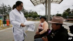 Un trabajador de la salud en Ecuador distribuye información a personas en una estación de bus, como parte de una campaña de prevención.