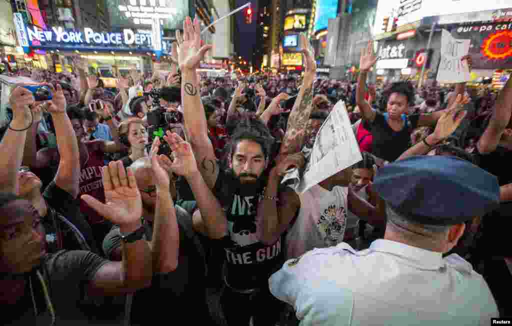 Protesters raise their hands during a peaceful demonstration, as communities react to the shooting of Michael Brown in New York's Times Square, Aug. 14, 2014.