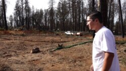 Valentin Martinez looks at what remains of his home, where he lived with his wife and son. Fleeing the fire, he was able to save a few things: his mother's and father-in-law's ashes and a few photos. (Elizabeth Lee/VOA)