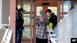 Police talk to a woman at housing commission apartments under lockdown in Melbourne, Australia, July 6, 2020. 