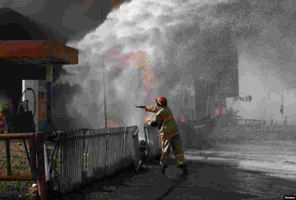 A firefighter standing near a Conoil petrol filing station directs his colleagues as to which direction to apply their hose, during a fire opposite the Nigeria National Petroleum corporation (NNPC) headquarters in Abuja.