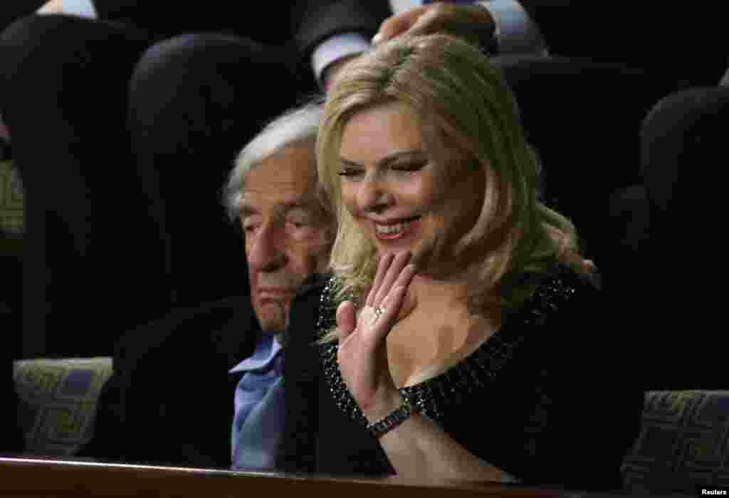 Sara Netanyahu, wife of Israeli Primine Minister Benjamin Netanyahu, waves as she sits next to Holocaust survivor and writer Elie Wiesel in the House Chamber prior to Prime Minister Netanyahu's address to a joint meeting of Congress in the House Chamber, Capitol Hill, Washington, March 3, 2015.