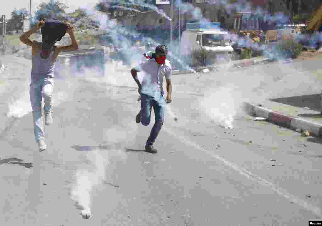 Para pengunjuk rasa Palestina melarikan diri dari gas air mata yang disemprotkan oleh pasukan Israel dalam bentrokan dekat penjara Israel Ofer di dekat kota Ramallah, Tepi Barat. 