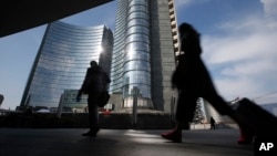 FILE - People walk in the Porta Nuova business center in Milan, Italy, March 11, 2016. 