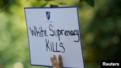 Seorang perempuan menunjukkan poster dalam demo anti penggunaan senjata dan supremasi kulit putih di depan Gedung Putih, Washington setelah penembakan massal di Dayton dan El Paso, 6 Agustus 2019.