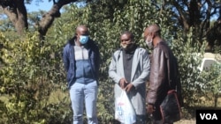 Les journalistes Samuel Takawira et Frank Chikowore aux côtés d'un inspecteur de police devant un tribunal à Harare, Zimbabwe, le 23 mai 2020. (Columbus Mavhunga/VOA) 