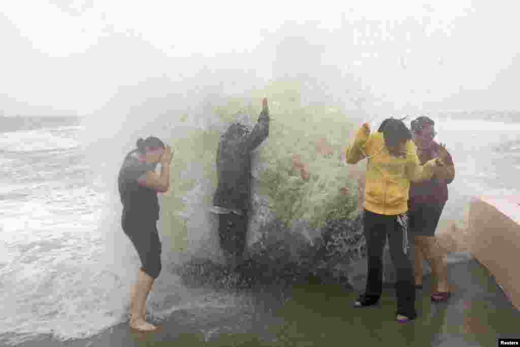 L-R: Denitsa Nakova, Abraham Robles, Laura Carrasco and Marilyn Rodriguez let the waves wash over them in Milford, Connecticut as Hurricane Sandy approaches the area, October 29, 2012.