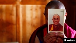 Seorang biksu membawa potret pemimpin spiritual Dalai Lama di Biara Labrang, Xiahe, Gansu (21/2/2012). 