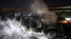 Asap mengepul dari sisa kendaraan milik pasukan perdamaian PBB di Lebanon (UNIFIL) yang dibakar para pedemo di jalan menuju Bandara Internasional Beirut, Jumat, 14 Februari 2025. (Foto: Ibrahim Amro/AFP)