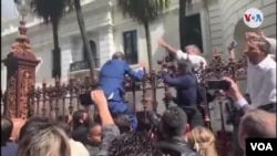 El presidente encargado de Venezuela, Juan Guaidó, al intentar saltar la verja de la Asamblea Nacional luego que militares les bloquearon el paso para intentar evitar su reelección como presidente legislativo. 