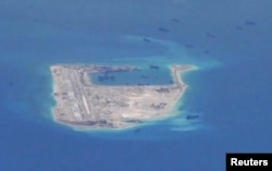 FILE - Chinese dredging vessels are purportedly seen in the waters around Fiery Cross Reef in the disputed Spratly Islands in the South China Sea in this still image from video taken by a P-8A Poseidon surveillance aircraft provided by the United States N